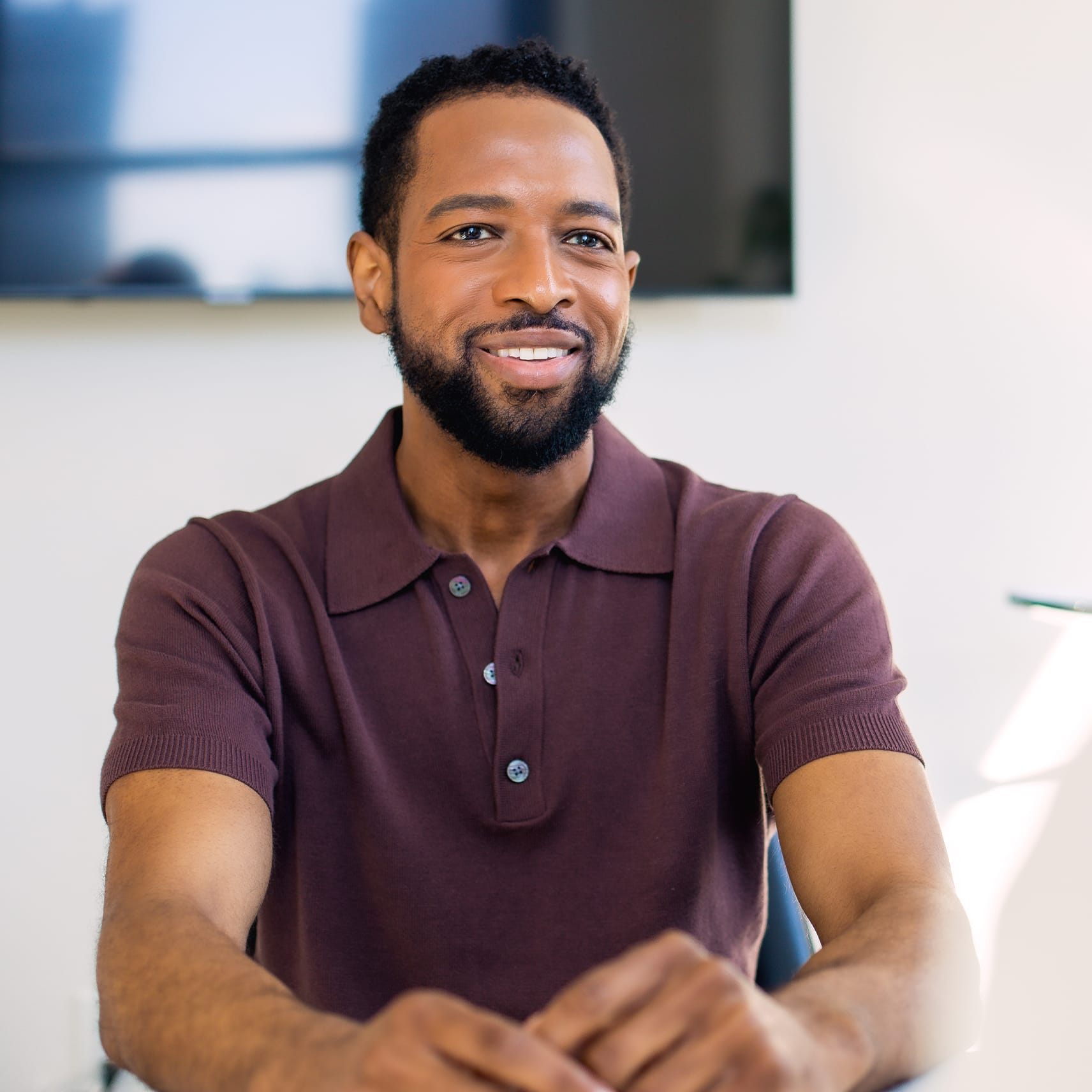 man in a maroon shirt smiling